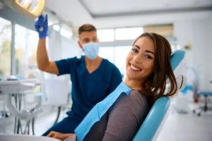 Young happy woman during teeth check-up at dental clinic looking at camera.