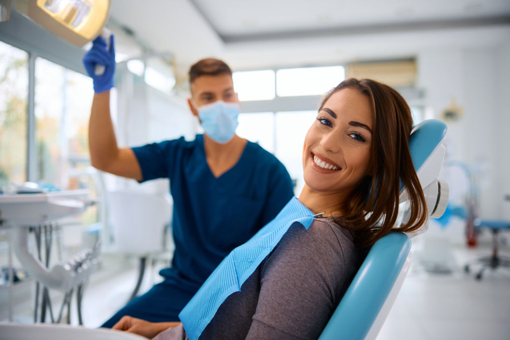 Young happy woman during teeth check-up at dental clinic looking at camera.